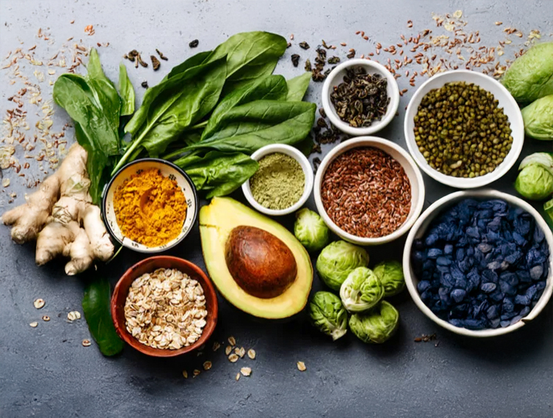 Assorted fresh herbs and superfoods including avocado and seeds